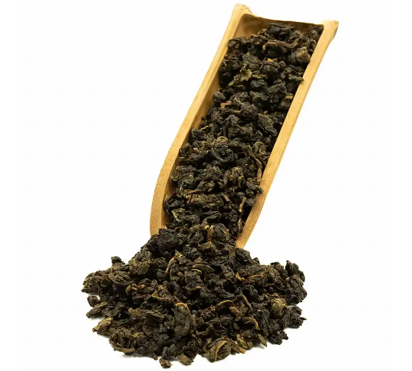 Suche, skręcone liście herbaty nasypane do drewnianej łyżki.