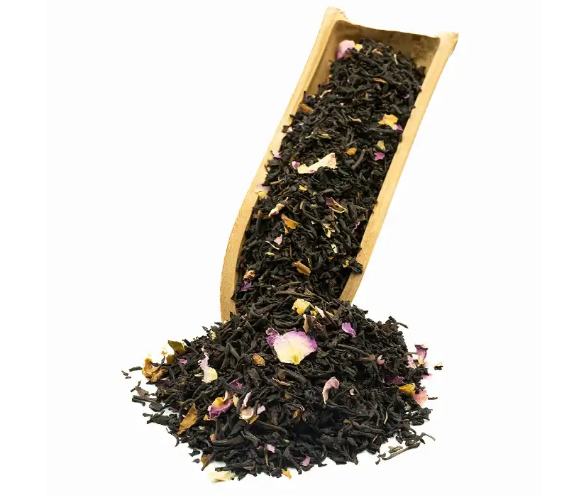 Suche, skręcone liście herbaty nasypane do drewnianej łyżki.