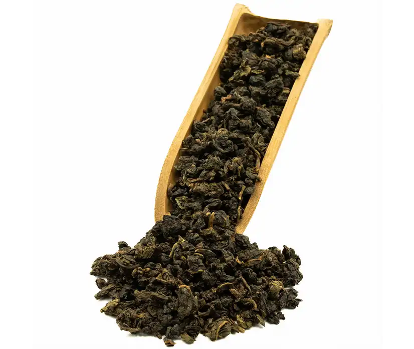 Suche, skręcone liście herbaty nasypane do drewnianej łyżki.